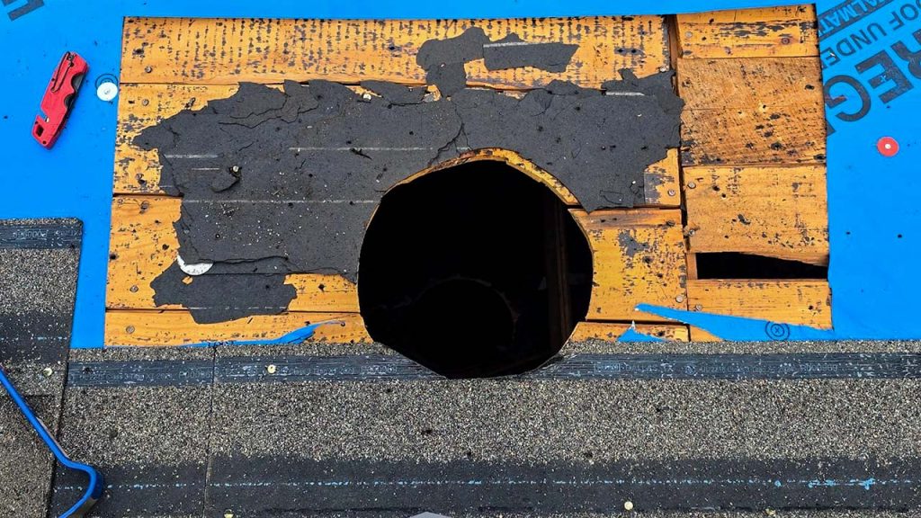 Shingles have been removed and the hole is in the roof is cut .