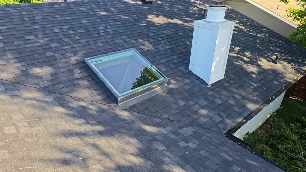 A roof displaying a skylight and chimney, emphasizing the recent addition of the skylight for improved lighting.