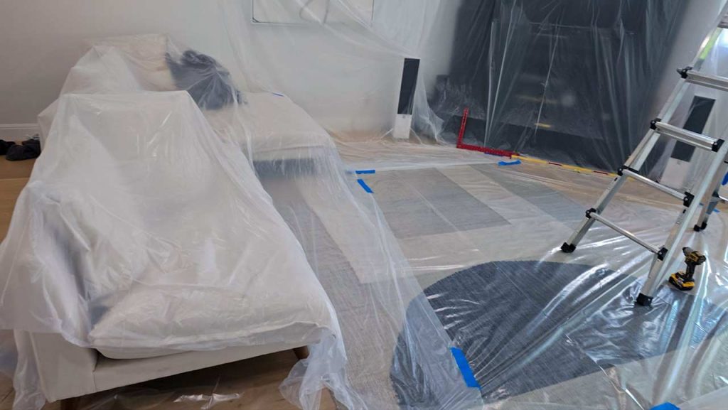 Interior view of a room with a couch wrapped in plastic sheeting, indicating protection from dust or damage.